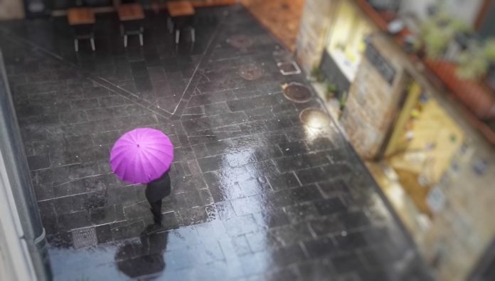 Paraigües Persona sota un paraigües rosa a la Bisbal d'Empordà ruixat xafec