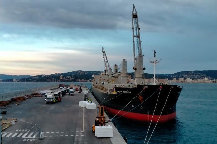 Un mercant descarregant pasta de paper a Palamós - Imatge de Ports de la Generalitat